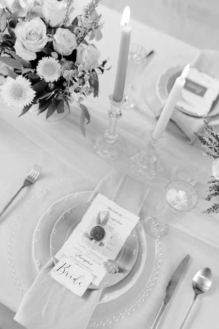Elegant black and white wedding table setup with flowers and candles.