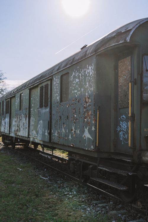 Free An old train car with graffiti sits abandoned on tracks under the sun. Stock Photo