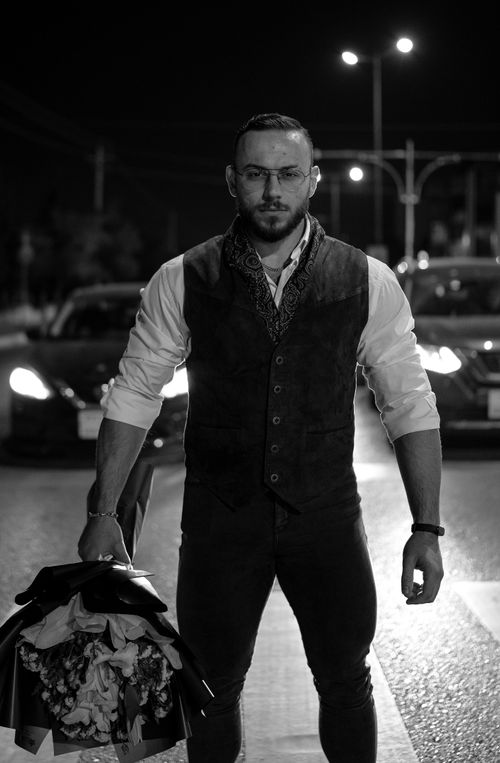 Free Stylish man holding flowers on Sulaymaniyah street, showcasing urban fashion at night. Stock Photo