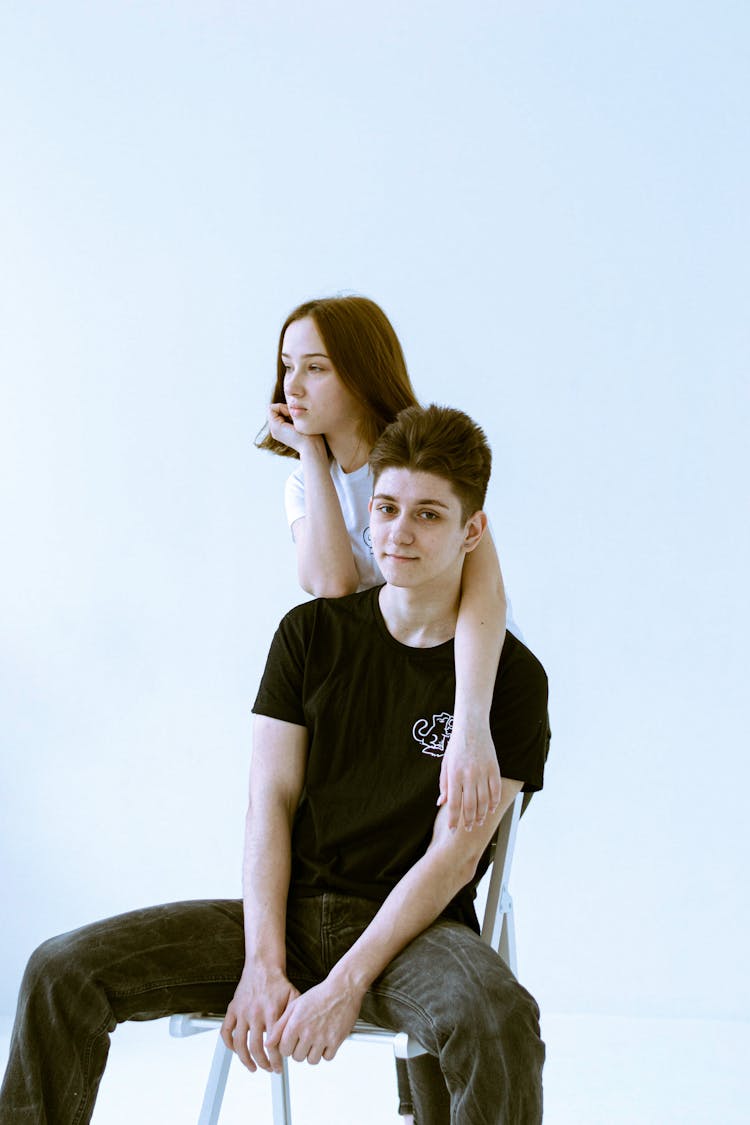 Woman Standing With Arm Wrapped Around Sitting Man