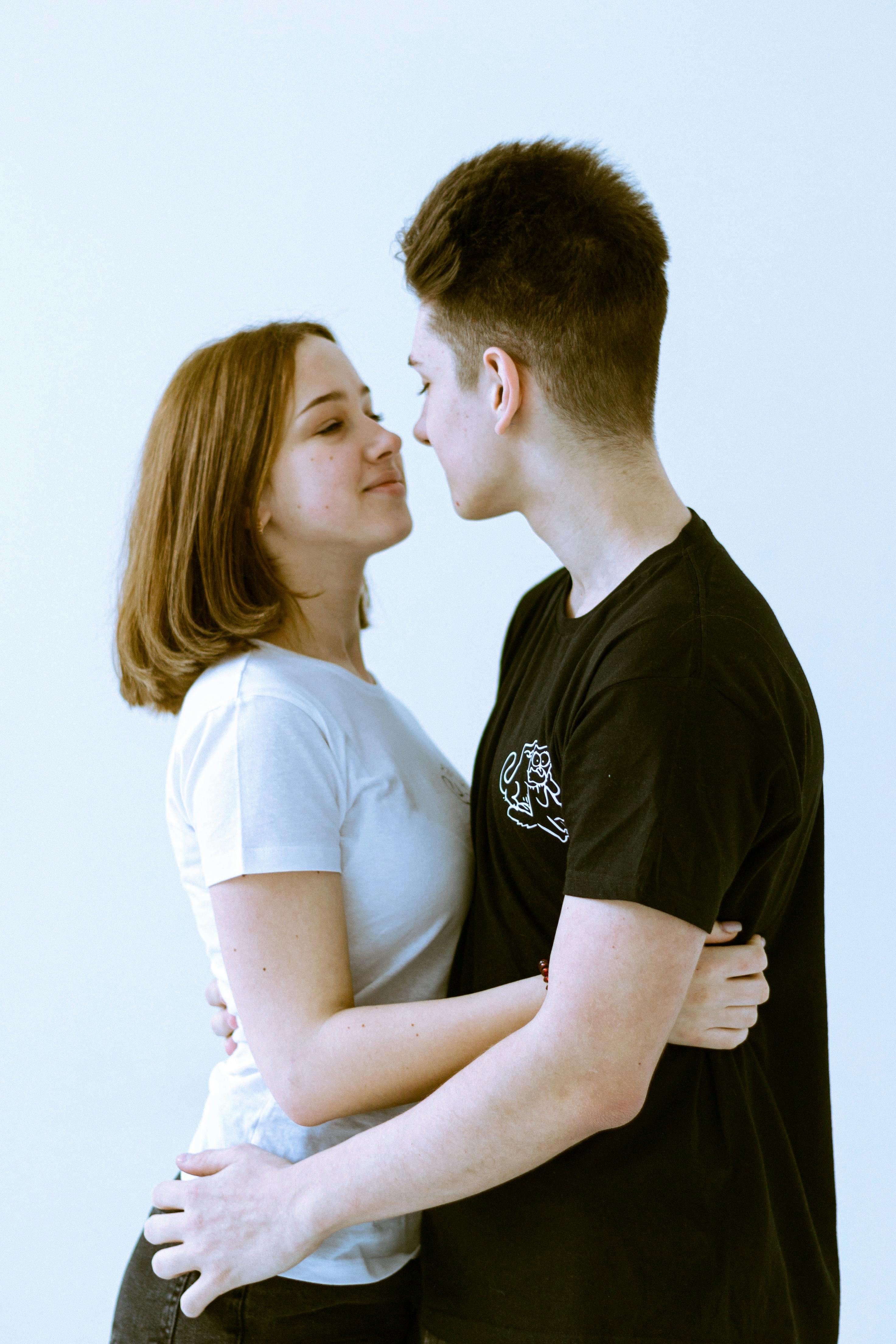 Close-up of a teenage couple embracing affectionately indoors, conveying warmth and connection.