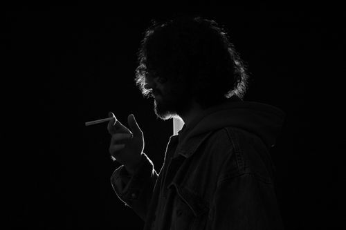 Free A moody black and white silhouette of a man smoking, emphasizing fashion and mystery. Stock Photo