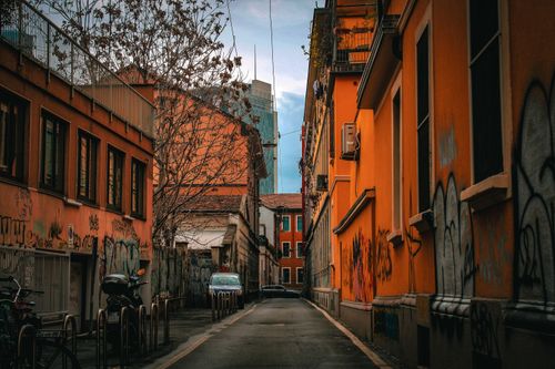 Free Narrow urban alley with colorful graffiti and parked bicycles, showcasing vibrant city architecture under a moody sky. Stock Photo