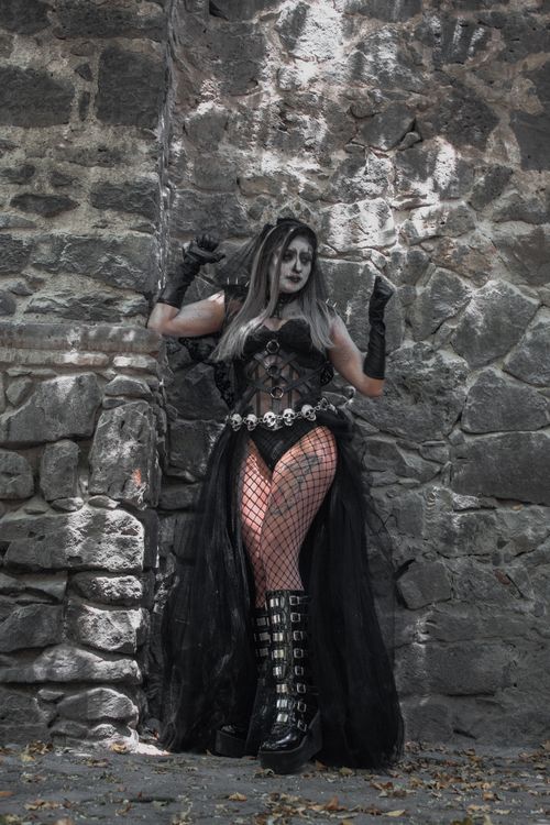 Free A gothic woman in Halloween costume poses against a textured stone wall. Stock Photo