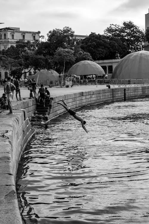 People Jumping to Water from Wall in Town