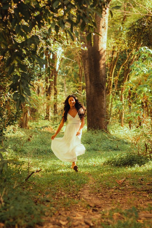 Young Woman Wearing a White Dress Taking a Stroll in the Forest