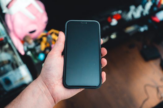 A hand holding a smartphone in a cozy indoor environment with a blurred background.