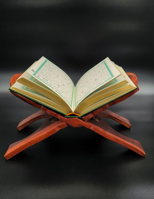 Free An opened Quran placed on a wooden stand against a dark background, symbolizing spiritual reflection. Stock Photo