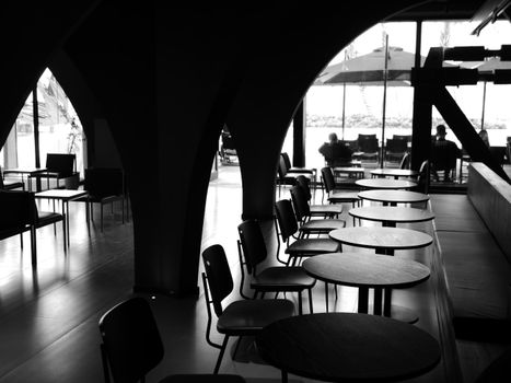 A black and white photo showcasing a modern restaurant interior with chairs and tables under archways.