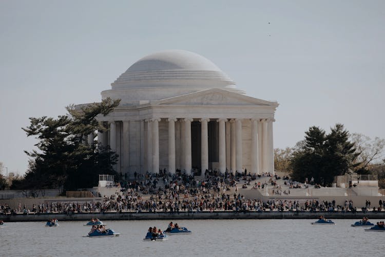 People Boating On River And Crowd Standing Near Thomas Jefferson Memorial