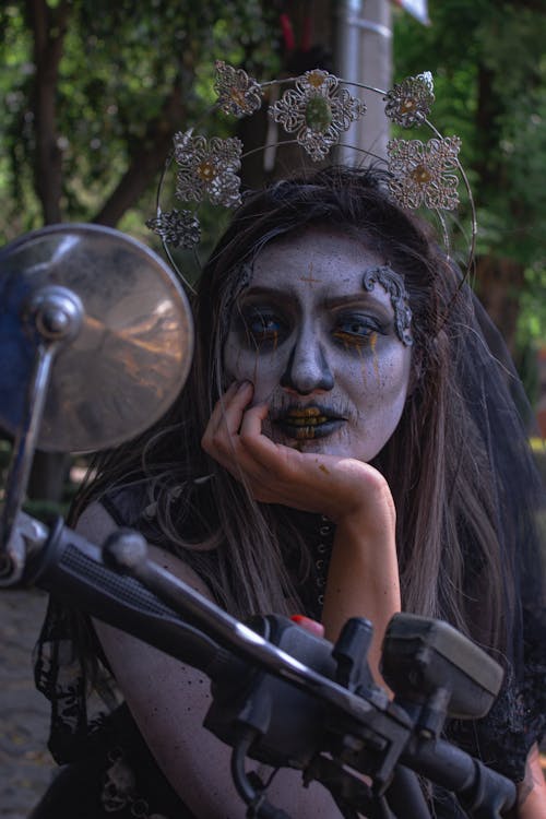 Woman in Halloween Costume Posing behind Motorbike Handlebar