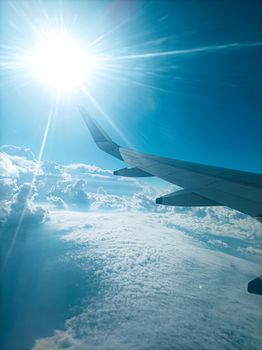 Stunning aerial view from an airplane wing with bright sun and clouds. Perfect for travel themes.