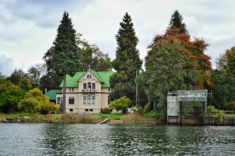 Clouds And Trees Around House On Riverbank