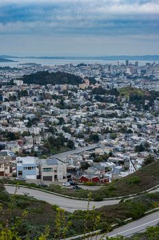 Aerial view of San Francisco cityscape with hills and bay under cloudy sky.