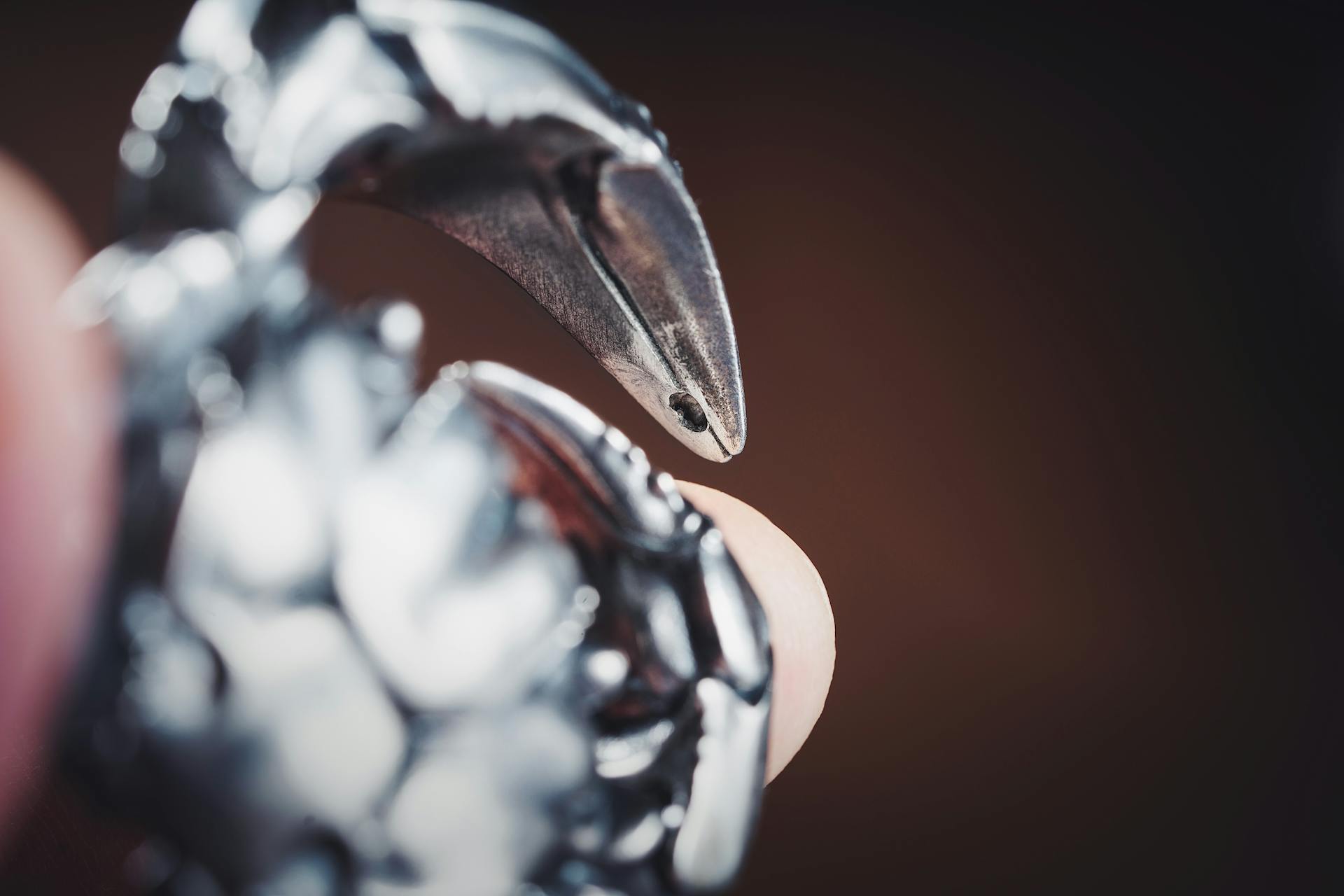 Detailed close-up of a metallic crab claw figurine keyring with focus on texture.