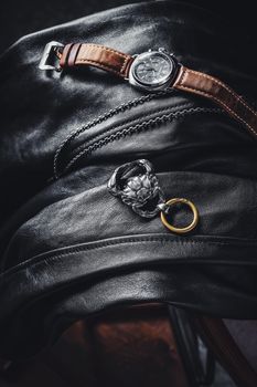 Stylish flat lay of leather jacket with a wristwatch and jewelry, perfect for fashion themes.