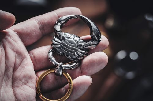 Free Close-up of a crab-shaped metal keychain held in a hand, showcasing intricate design details. Stock Photo