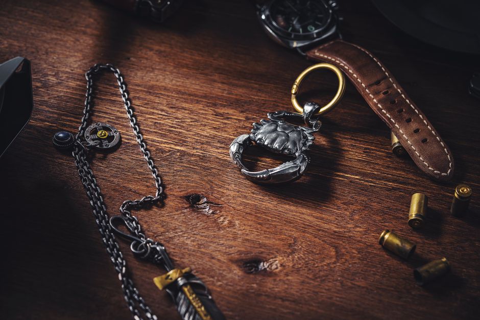 A stylish flat lay featuring a silver crab keychain on a wooden table, surrounded by unique accessories.