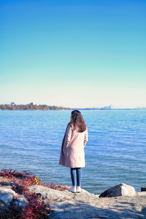 Woman in Coat Standing on Sea Shore