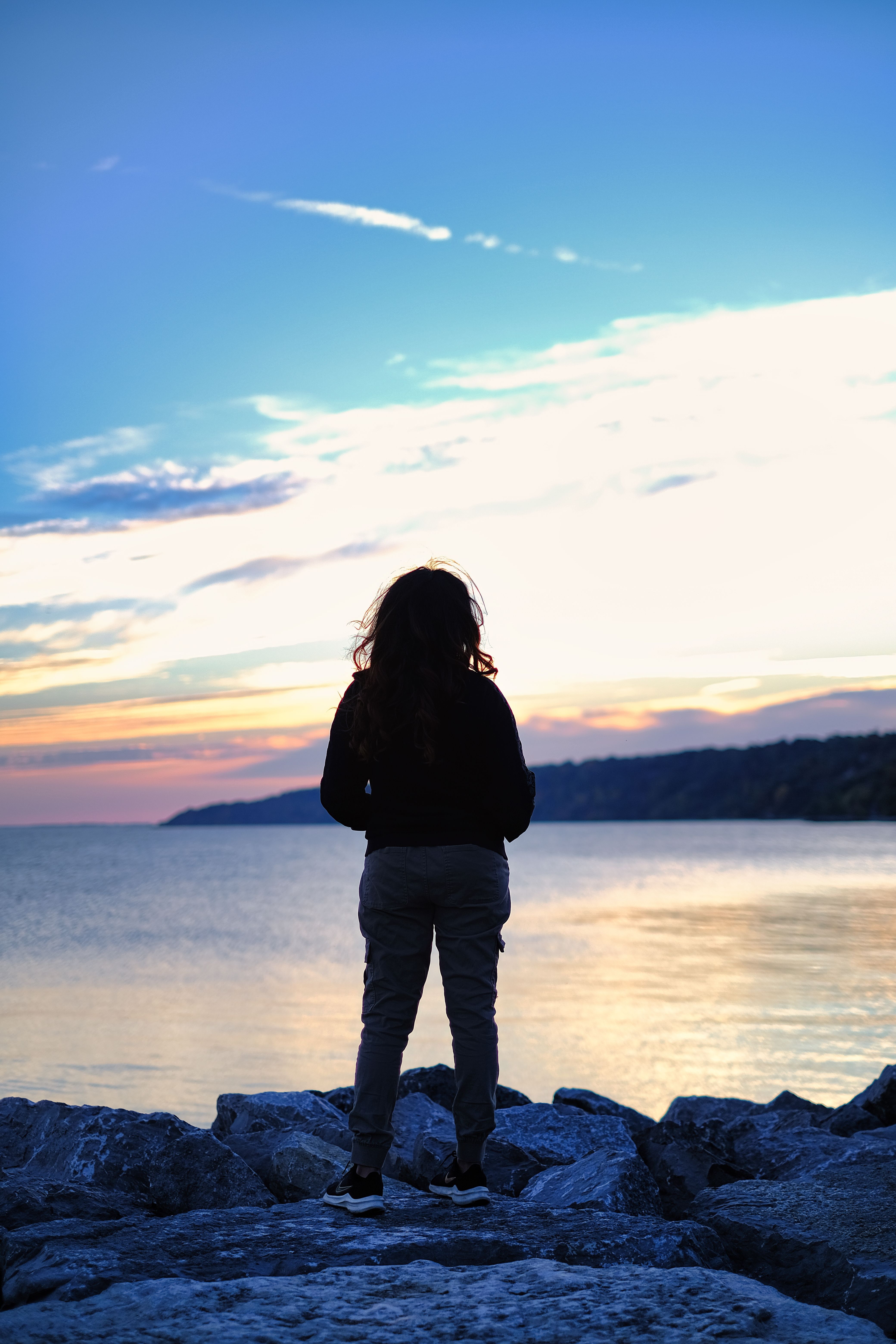 Silhouette of a Woman Standing on a Shore at Dawn · Free Stock Photo