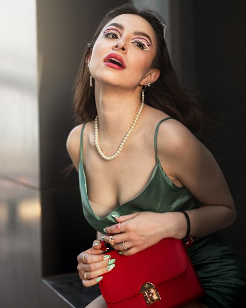 Free Stylish woman in elegant green dress and artistic makeup holding a red bag. Stock Photo