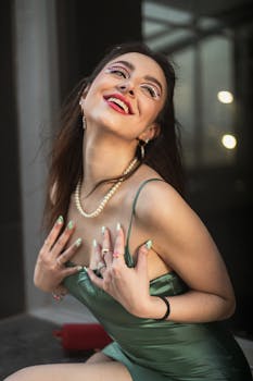 Glamorous young woman in a green dress with artistic makeup and jewelry.