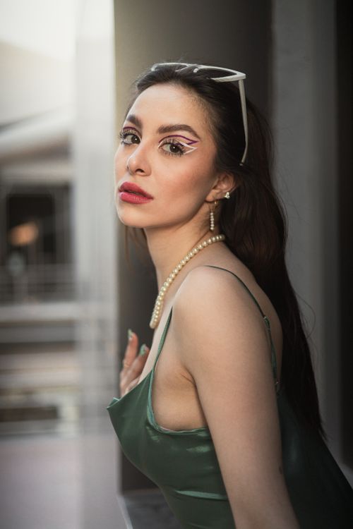 Free Stylish portrait of a woman wearing artistic makeup, elegant dress, and accessories, exuding charisma. Stock Photo
