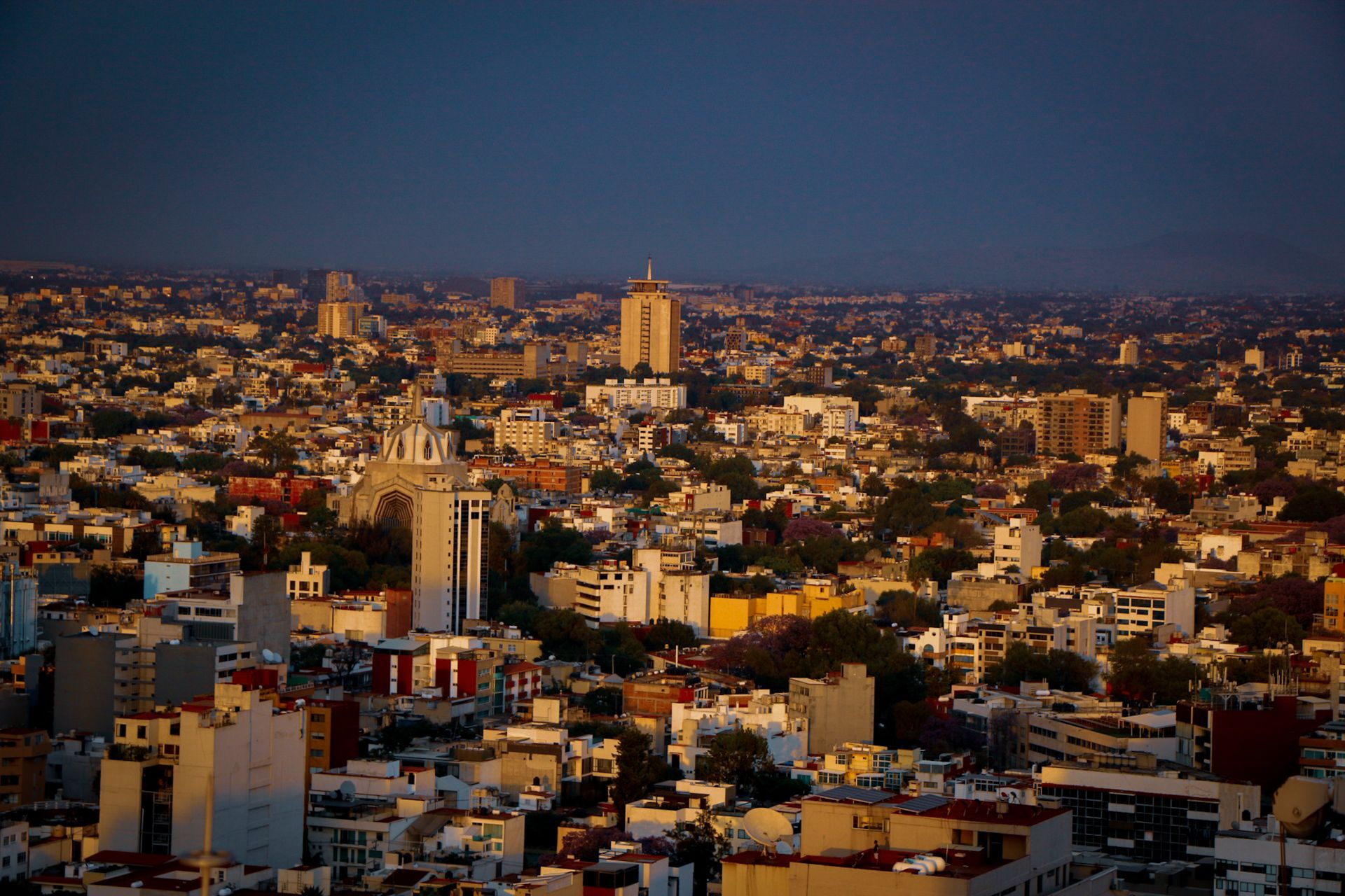 Aerial view of Guadalajara cityscape during sunset, showcasing vibrant buildings and warm colors.