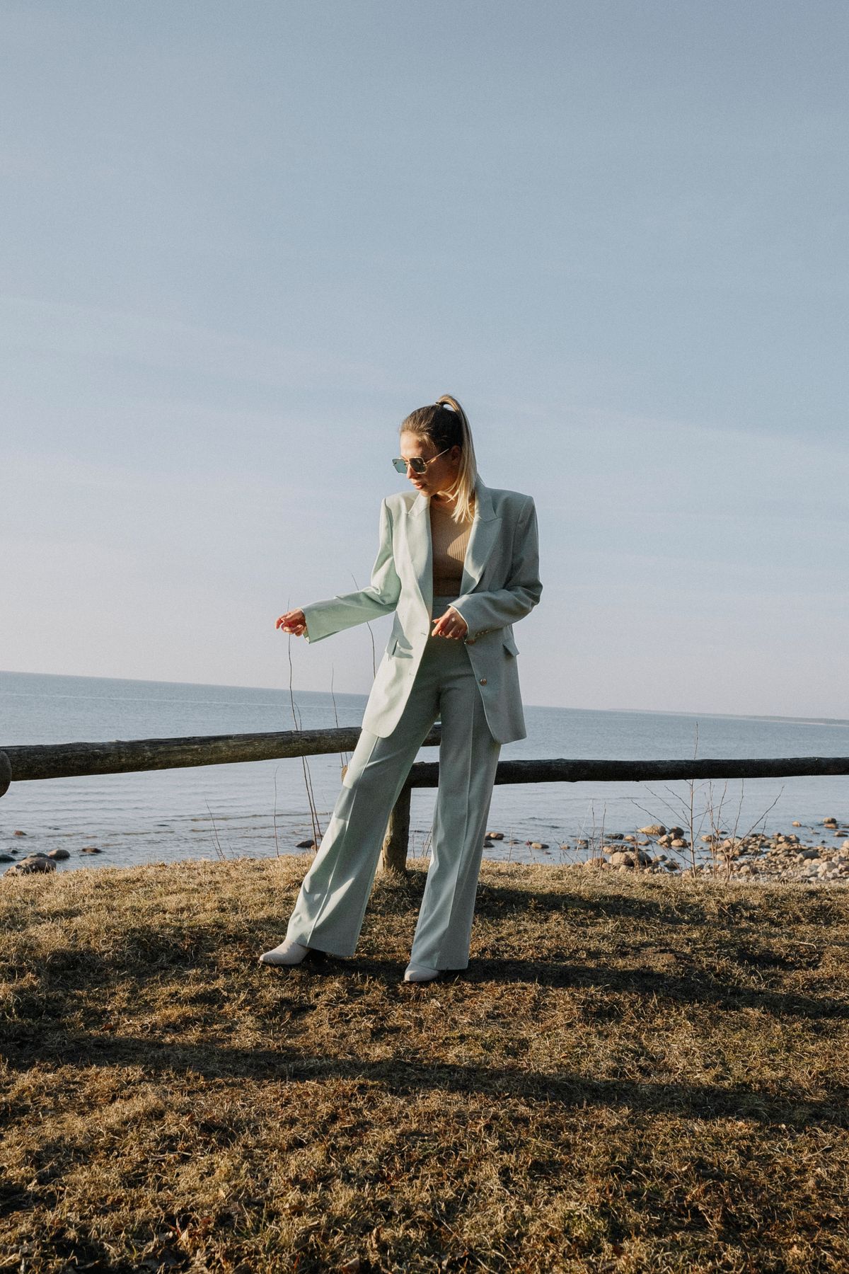 A model in a light grey suit on the coast — fluid tailored trousers in summer
