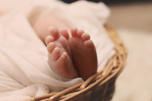 棕色柳條籃上的嬰兒的腳