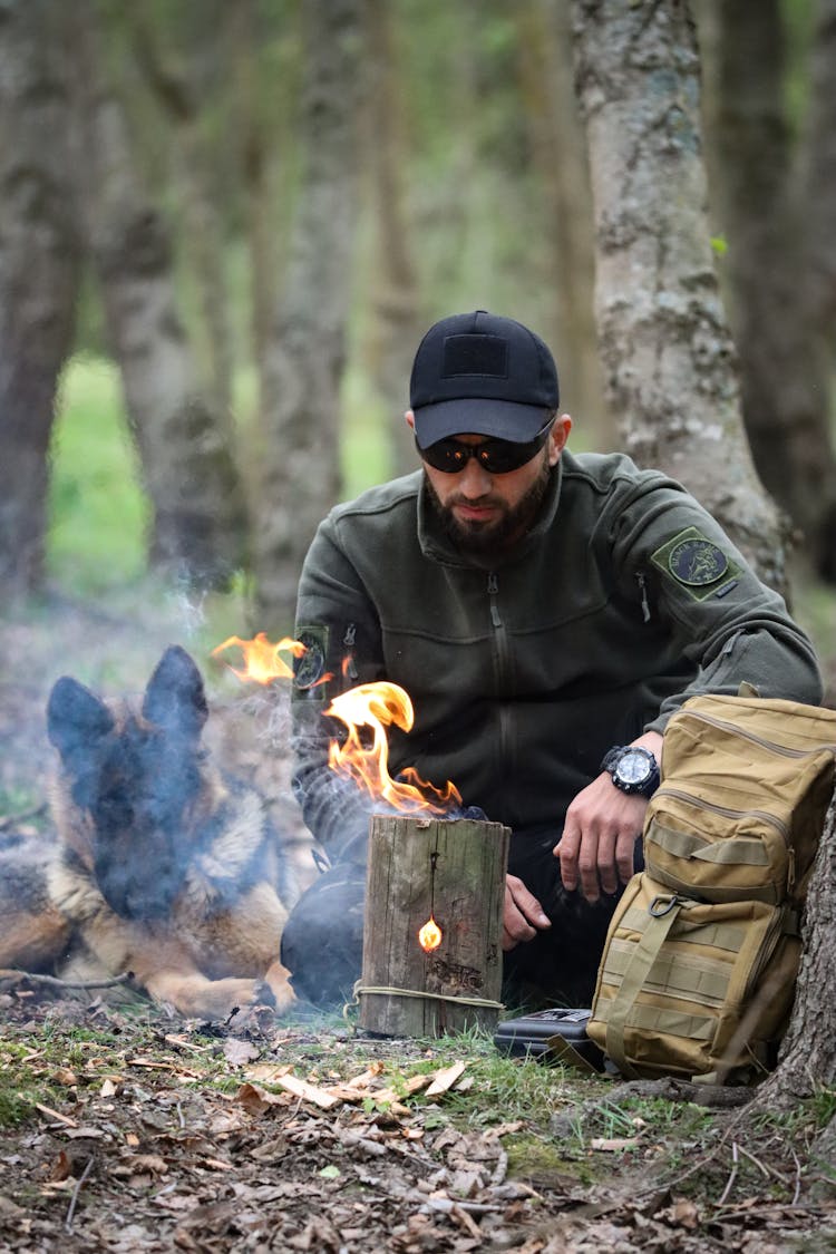 Man With A German Shepherd Sitting By A Campfire