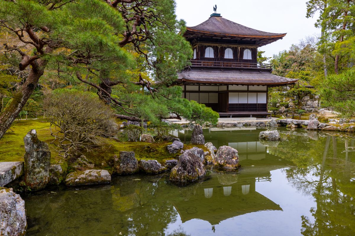 A traditional Japanese garden with stone lanterns, moss and a small temple pond at a hot spring resort