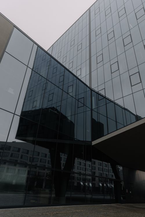 Free Contemporary building with reflective glass walls under overcast sky. Stock Photo