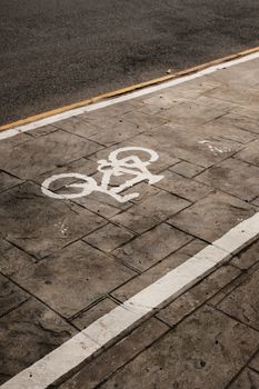 Close-up view of a bike lane on city streets with a cyclist pictograph painted on the sidewalk.