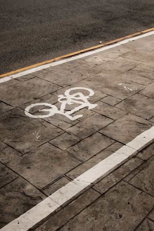 Free Close-up view of a bike lane on city streets with a cyclist pictograph painted on the sidewalk. Stock Photo