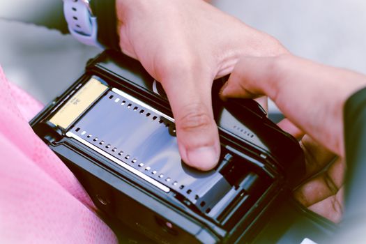 Hands loading film into a vintage camera, highlighting an analog photography process.