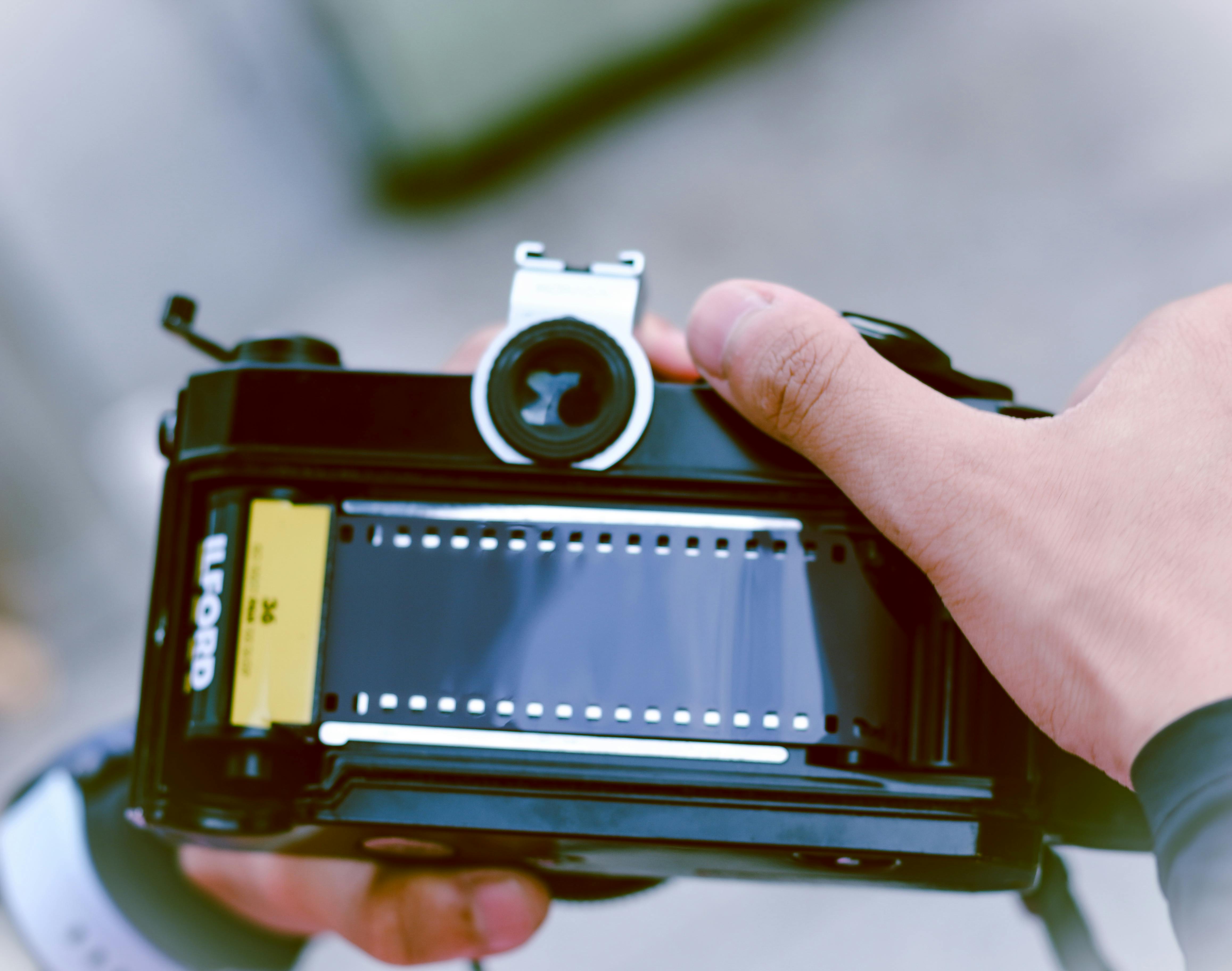 A close-up of hands handling a vintage film camera, showcasing analogue photography.