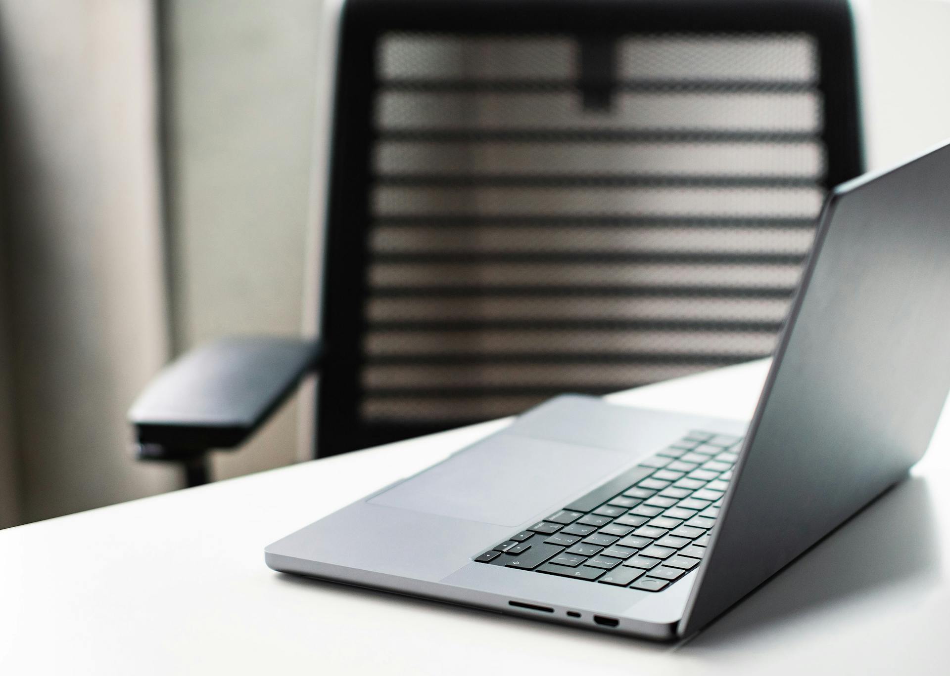 A sleek laptop on a white desk in a modern office setting, ideal for business use.