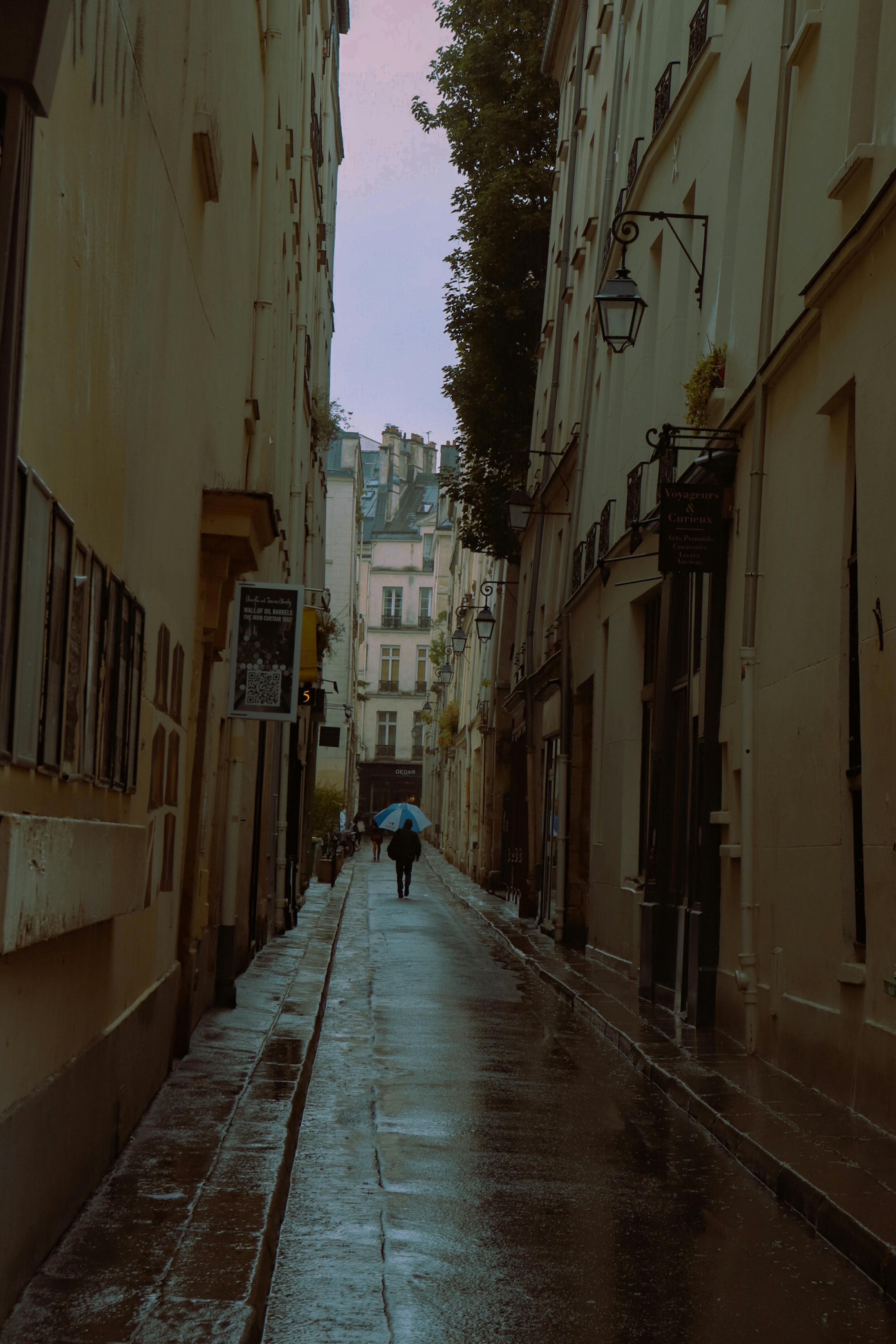 a person walking down a narrow street in the rain