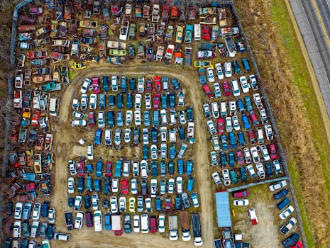 Drone view of a sprawling car junkyard with vintage vehicles in Rochester, MN.