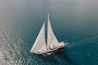 一艘经典的帆船在晴朗的天空下穿过原始的蓝色海水