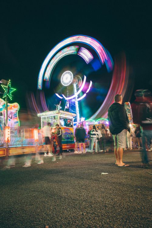 Free Long exposure shot capturing a vibrant, illuminated ferris wheel and blurred motion at a night carnival. Stock Photo