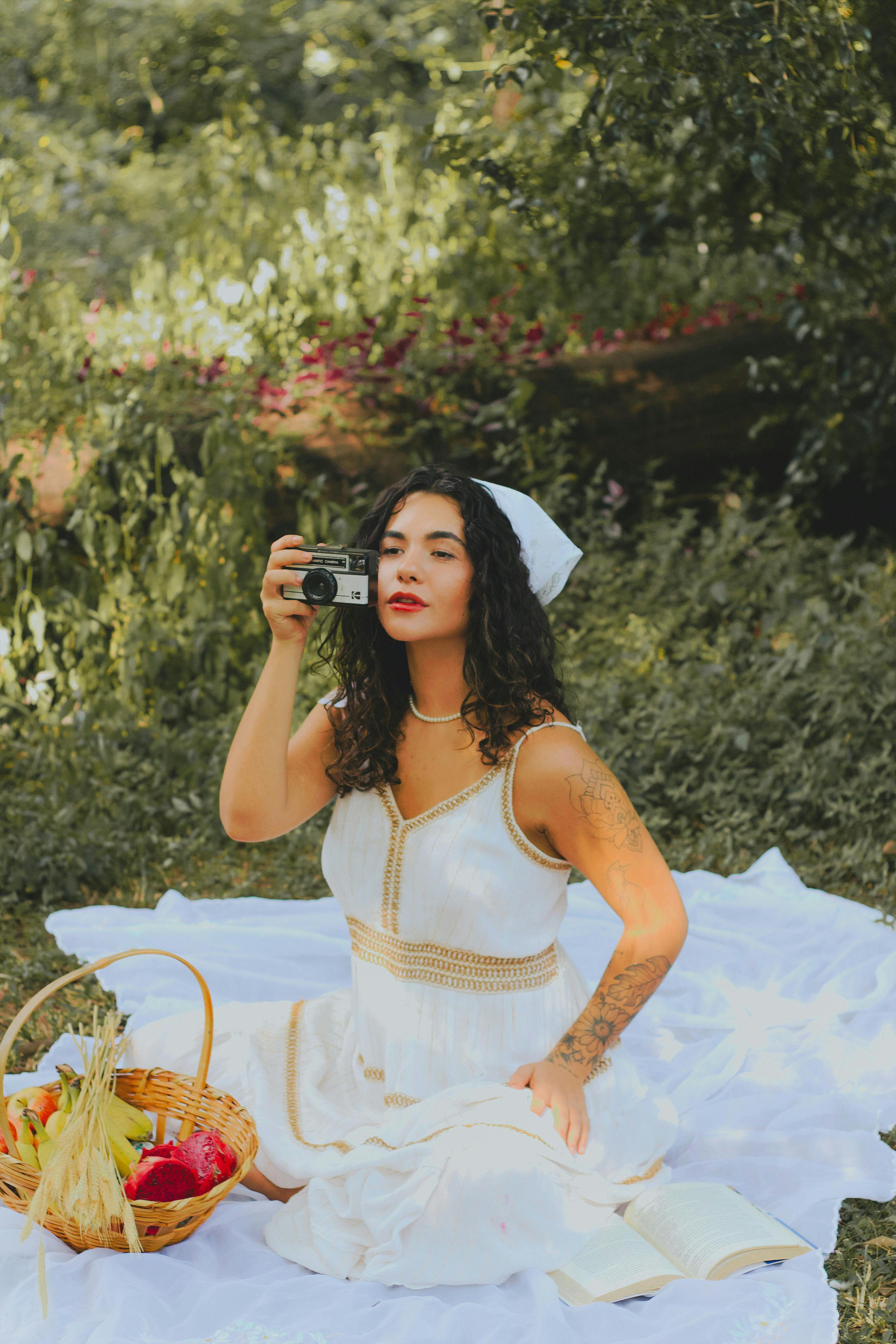 A woman in a white dress enjoys a picnic with a camera on a sunny day in Belo Horizonte.