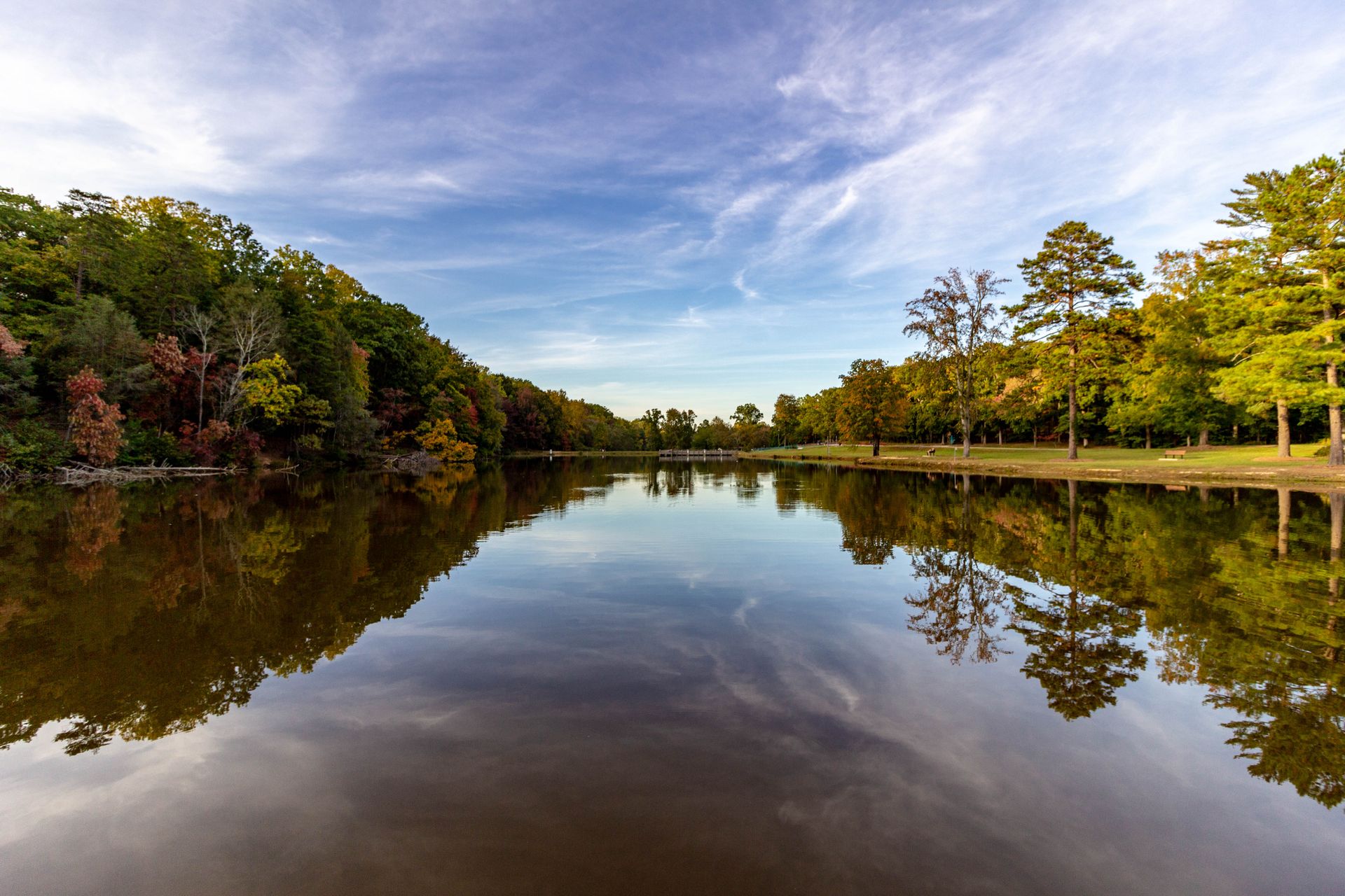 Majestic autumn landscape with tree reflections in a serene Greensboro park.