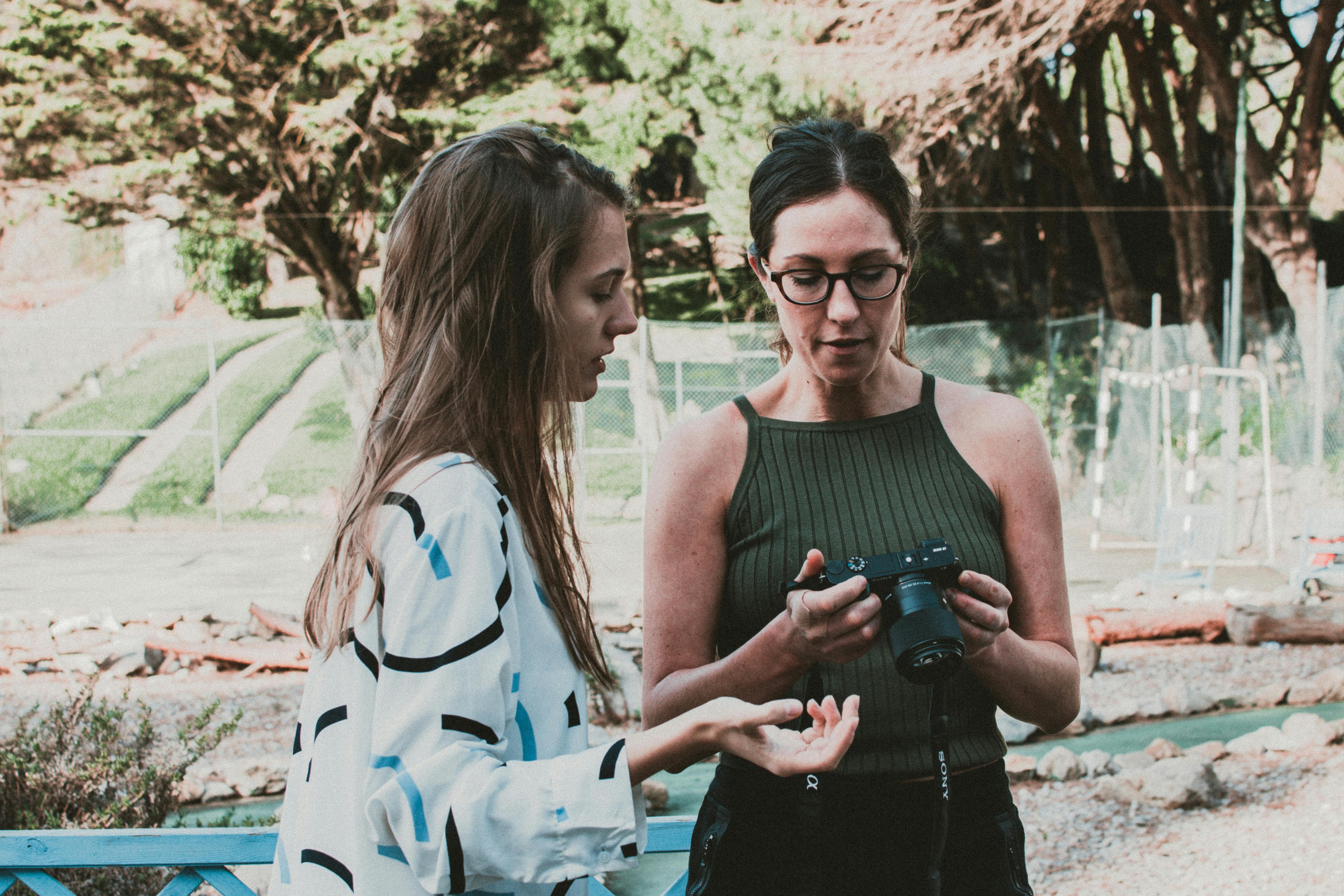 woman standing near woman holding camera