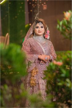 Beautiful South Asian bride standing in traditional dress with intricate embroidery.
