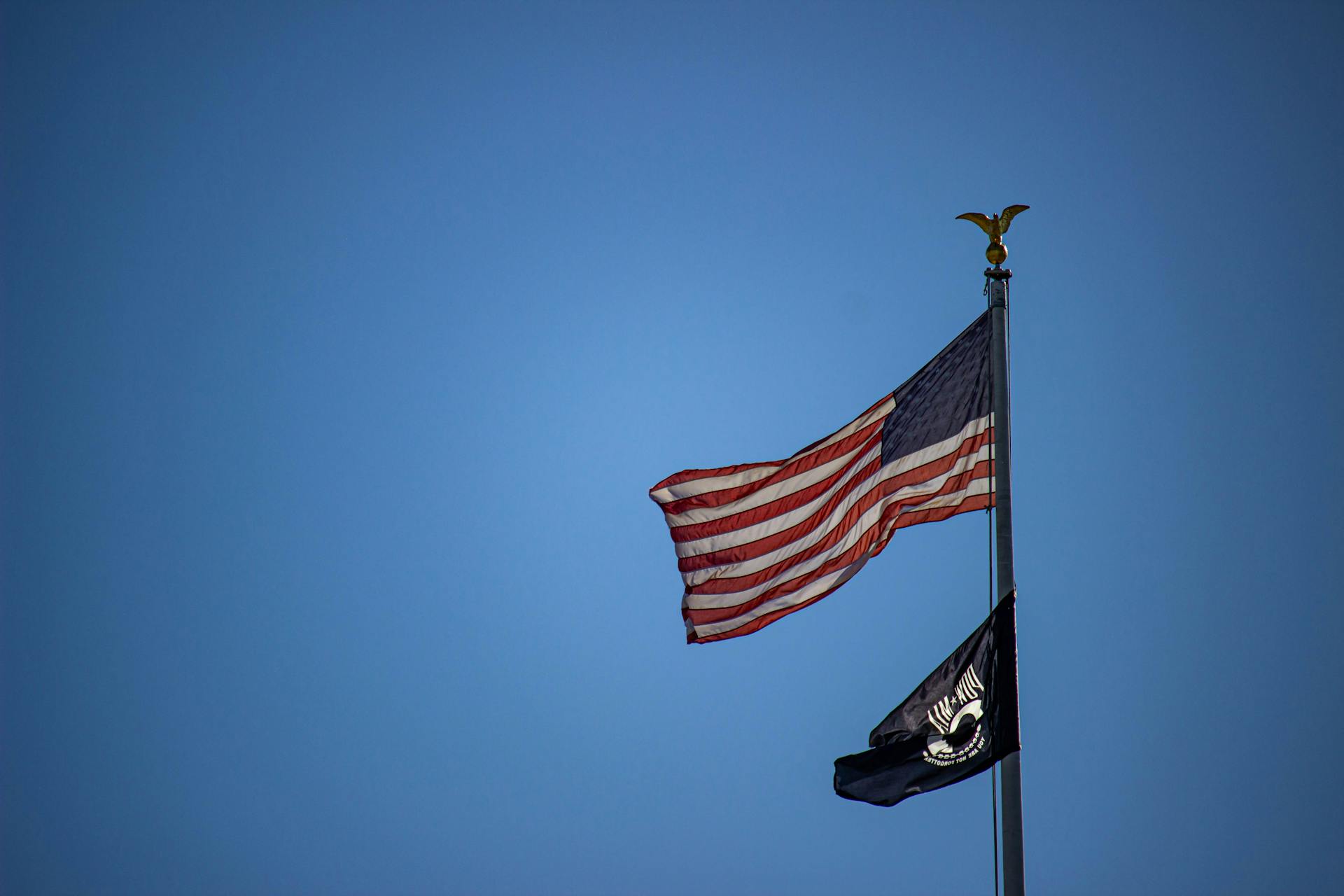 Flagpole with the Flags of the United States of America and the National League of Families POW MIA