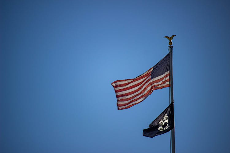 Flagpole With The Flags Of The United States Of America And The National League Of Families POW MIA