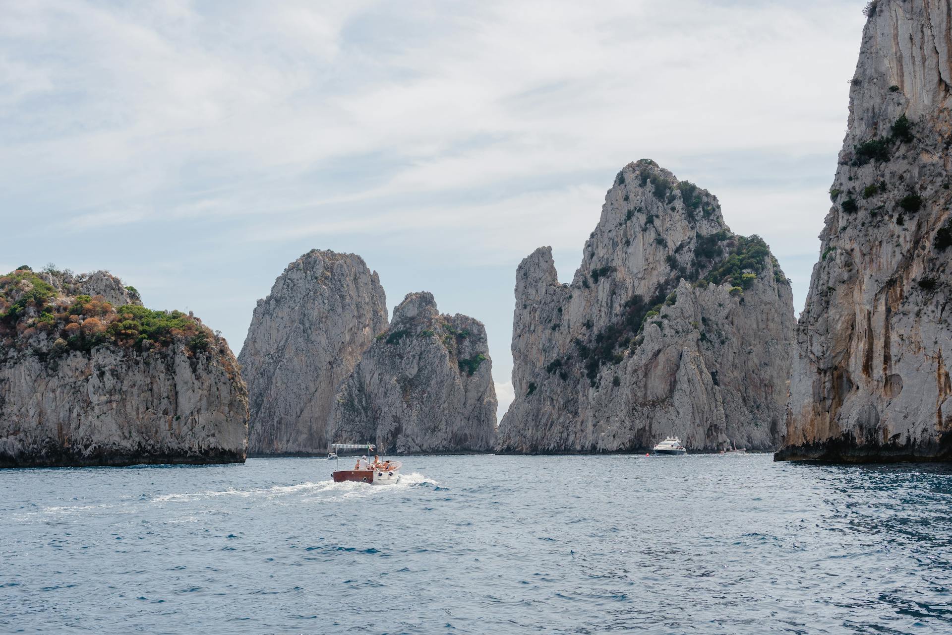 Explore the stunning limestone cliffs of Capri with boats cruising through the azure waters.