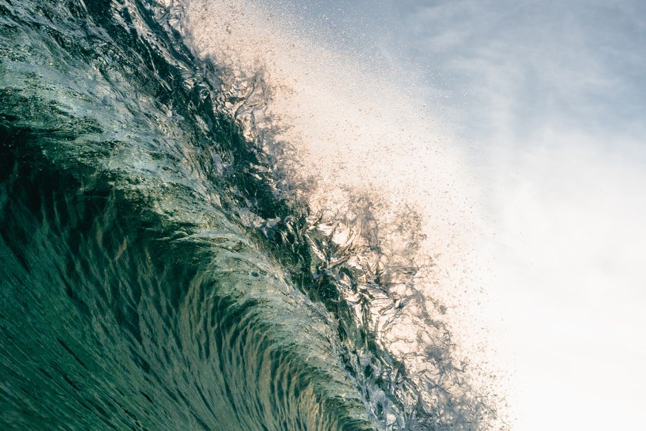 Capture the power of nature with a close-up of a vibrant ocean wave under daylight.